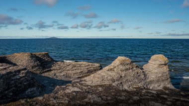 İsveç 'teki ada kıyısındaki kireçtaşı kayalıkları güneş ve mavi gökyüzüyle