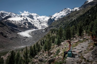 İsviçre Alpleri 'ndeki Engadin' de karlı dağları olan Morteratsch Buzulu 'na bakan bir kadın. Yazın mavi gökyüzü ve suyla.