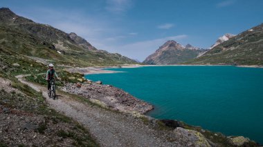 Güneşli Bernina Geçidi 'ndeki Lago Bianco barajında dağ bisikleti.