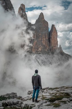 Dolomite Alpleri 'nin önünde, İtalya' daki Three Peaks 'te kameralı fotoğrafçı. Auronzo Lavaredo' da Dolomitlerin yanından alçak bulutlar geçiyor.