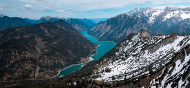Turquoise colored Lake Plansee with mountains in Tyrol Austria during sunny blue sky weather from above