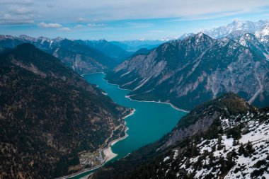 Turquoise colored Lake Plansee with mountains in Tyrol Austria during sunny blue sky weather from above
