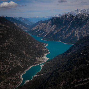 Turquoise colored Lake Plansee with mountains in Tyrol Austria during sunny blue sky weather from above