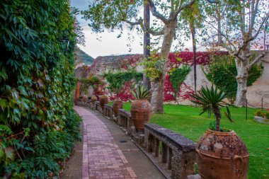 Amalfo kıyısındaki eski villa Cimbrobne 'ye (Ravello) giden patika ve duvarlarda kırmızı sarmaşık - Güney İtalya' da muhteşem bir sonbahar, Campania.