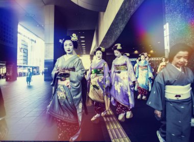 03 / 28 / 2015 Kyoto Japonya. Maiko - Geyşa ya da geyşa öğrencileri, kimono giymiş genç kadınlar, Kyoto istasyonunun yanında tahta üzerinde yürüyorlar. Hipster tarzı efekt.