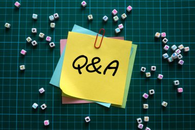 Yeşil kare arkaplan üzerinde Q & A ile yazılmış alfabe boncukları ve notlarının üst görünümü.