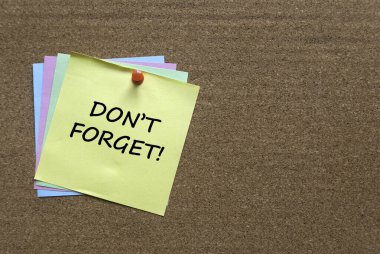 A stack of memo notes written with Don't Forget on a cork board.