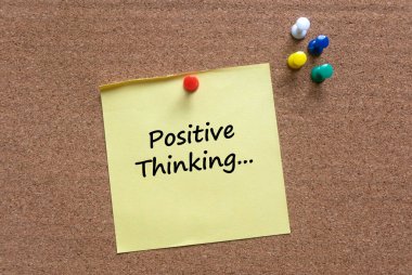 Renkli bir raptiye ve bir mantar mantara olumlu düşünme ile yazılmış sarı bir not..