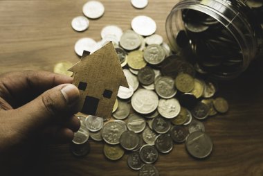 Bozuk para kavanozunun en üst görüntüsü ve ahşap arka planda karton ev..