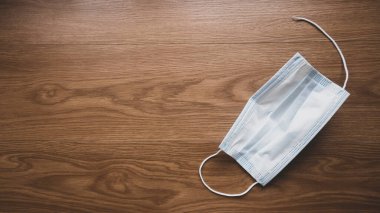 Kullanılmış ve kırılmış yüz maskesinin seçmeli odak noktası tahta zemin üzerinde kopyalama alanı ile.