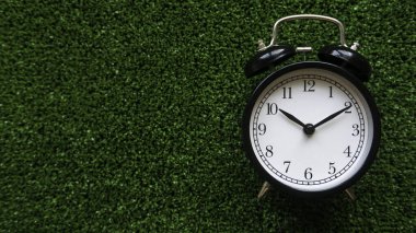 Yeşil çimen arka planında kopyalama alanı olan klasik bir alarm saati.