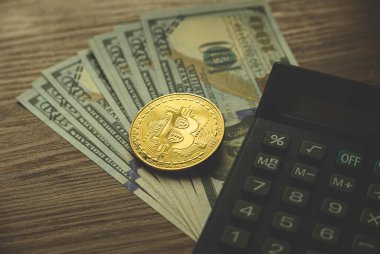 Altın bitcoin 'in seçici odak noktası dolar banknotları ve ahşap arka planda hesap makinesi. Kripto para birimi kavramı.