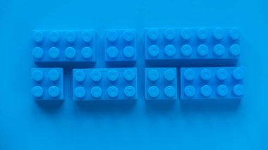 Blue plastic building blocks on blue background.