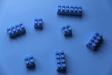 Blue plastic building blocks on blue background.