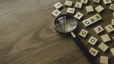 Q&A or questions and answers concept .Selective focus of wooden alphabet and magnifying glass on wooden background with copy space.