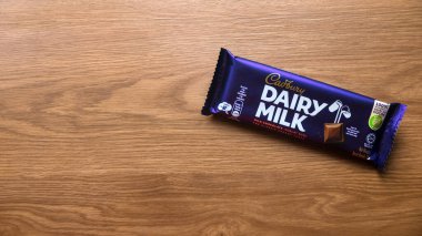 KEDAH, MALAYSIA - 6 Mart 2021: Ahşap arka planda Cadbury Süt Çikolatası. Cadbury Dairy Milk, Cadbury tarafından üretilen bir süt çikolatasıdır..