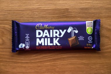 KEDAH, MALAYSIA - 6 Mart 2021: Ahşap arka planda Cadbury Süt Çikolatası. Cadbury Dairy Milk, Cadbury tarafından üretilen bir süt çikolatasıdır..