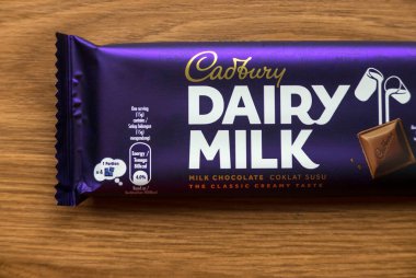 KEDAH, MALAYSIA - 6 Mart 2021: Ahşap arka planda Cadbury Süt Çikolatası. Cadbury Dairy Milk, Cadbury tarafından üretilen bir süt çikolatasıdır..