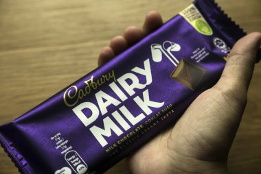 KEDAH, MALAYSIA - 6 Mart 2021: Cadbury Süt Çikolatası 'nı tutan bir el. Cadbury Dairy Milk, Cadbury tarafından üretilen bir süt çikolatasıdır..
