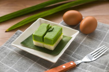 Geleneksel Malezya tatlısı Kuih Seri Muka 'nın seçici odak noktası buharda pişmiş glutinöz pirinçli iki tatlı alt yarısını oluşturuyor ve pandan suyundan yapılmış yeşil krema tabakası..