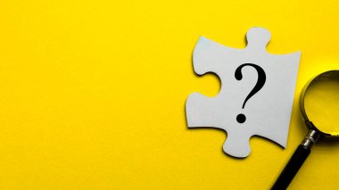 Questions symbol on a white piece of jigsaw puzzle on a yellow background with copy space.