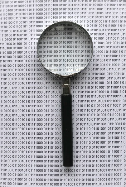 Top view of magnifying glass on a paper sheet of binary code.