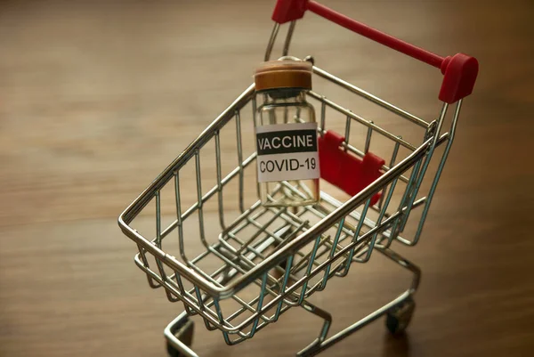 A concept of an emergency and urgent COVID-19 vaccine distribution. Selective focus of a bottle of covid-19 vaccine on a shopping cart.