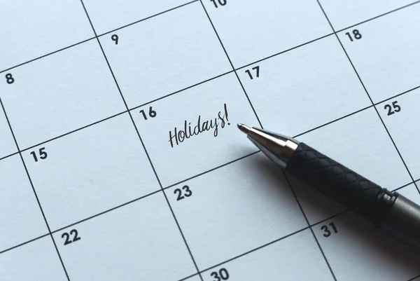 Selective focus of pen and calendar with a reminder of Holidays.