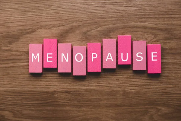 Ahşap zemin üzerinde menopoz metni olan pembe bir tahta blok..