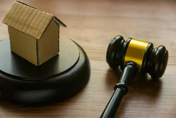 Real estate law & property auction concept with gavel and house model on wooden background.