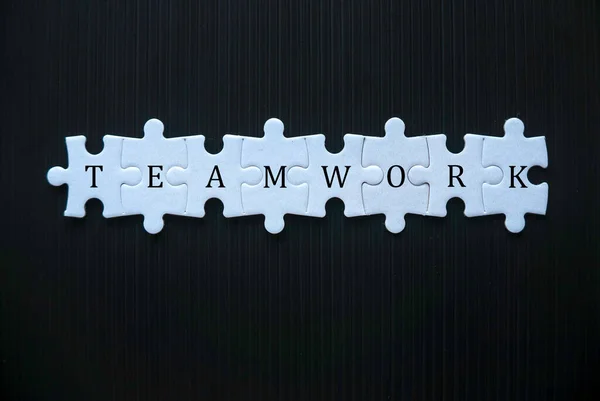 Jigsaw puzzle concept of teamwork on black background.