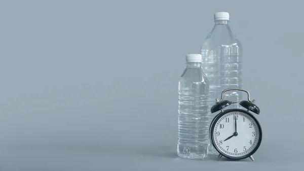A plastic bottle of drinking water and vintage alarm clock isolated on grey background with copy space.