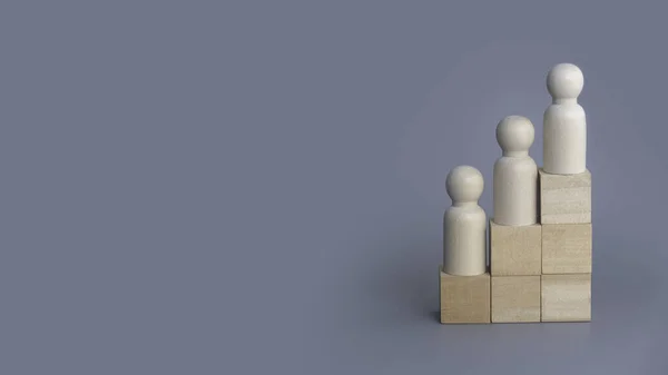 Wooden people on stairs on grey background with copy space.