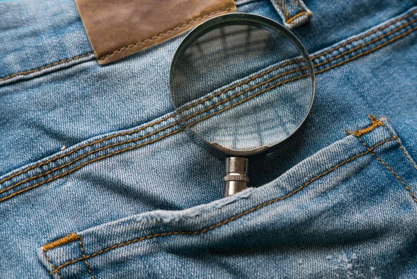 Magnifying glass at the back of blue jeans pocket. Search concept.
