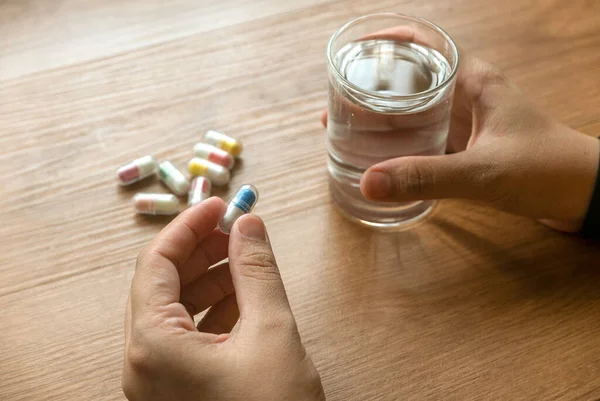 People taking medicine with a glass of drinking water.