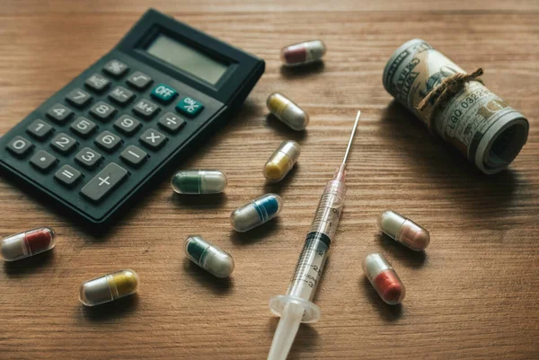 Medical expenses concept.Calculator, spilled pills,syringe and banknotes.