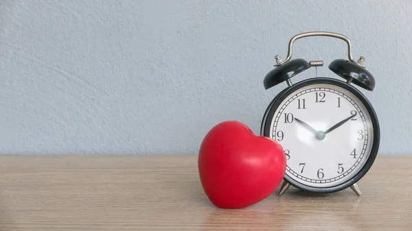 A vintage alarm clock with red heart love on table with copy space.