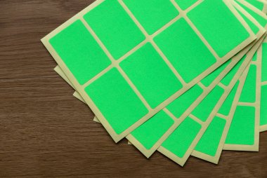 A set of green rectangular paper sticker label on wooden background.