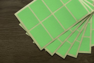 A set of green rectangular paper sticker label on wooden background.