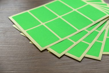 A set of green rectangular paper sticker label on wooden background.