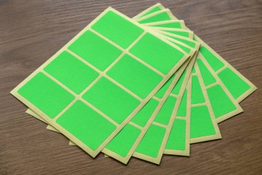 A set of green rectangular paper sticker label on wooden background.