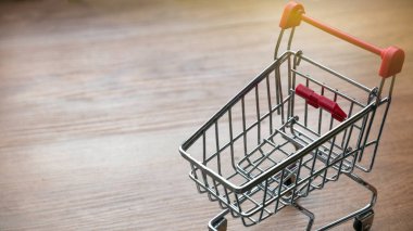 Boş bir alışveriş arabası ahşap arka planda fotokopi alanı ile.