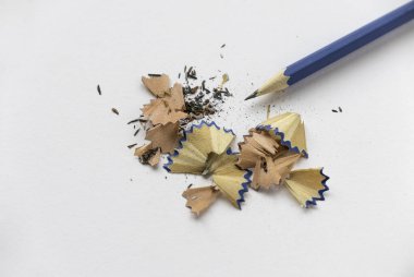 Mavi kalem ve talaşı, kırıntıları ve tozları beyaz kağıt üzerinde..
