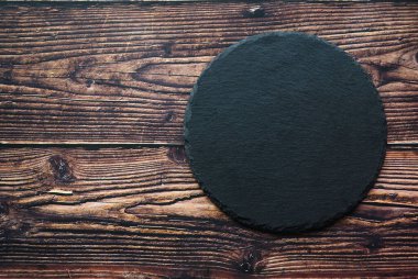 Tahta zemin üzerindeki siyah yuvarlak taşın fotokopi alanı ile üst görünümü.