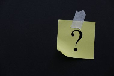 Soru sembolü ile yazılmış siyah duvara yapıştırılmış sarı kağıt.