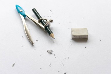 Geometrik pusulalar ve silgi beyaz kağıt arka planda tozlu.