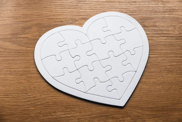 Selective focus of heart or love shape jigsaw puzzle on a wooden background.