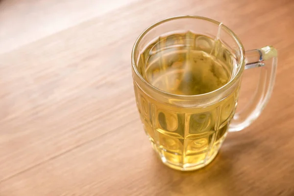 Selective focus of a glass of tea with a tea bag on a wooden background.