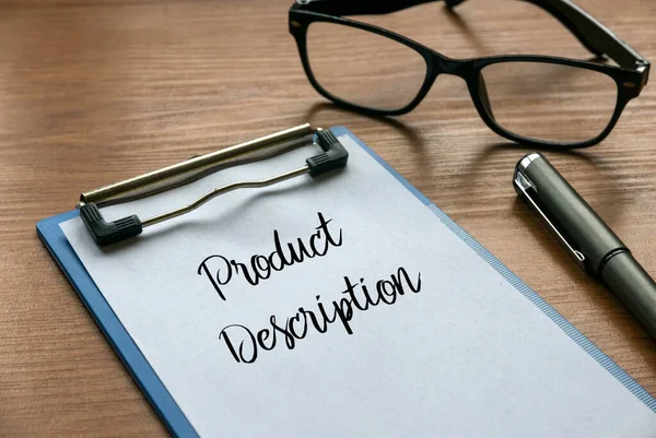 Selective focus of glasses, pen, clipboard and paper written with Product Description on wooden background.