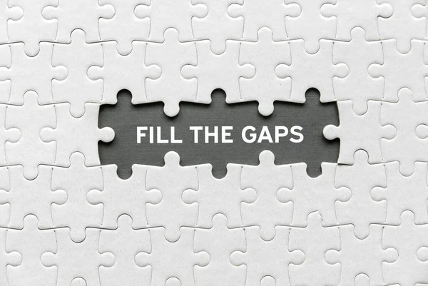 Top view of an empty space of jigsaw puzzle fill with a phrase Fill The Gaps.